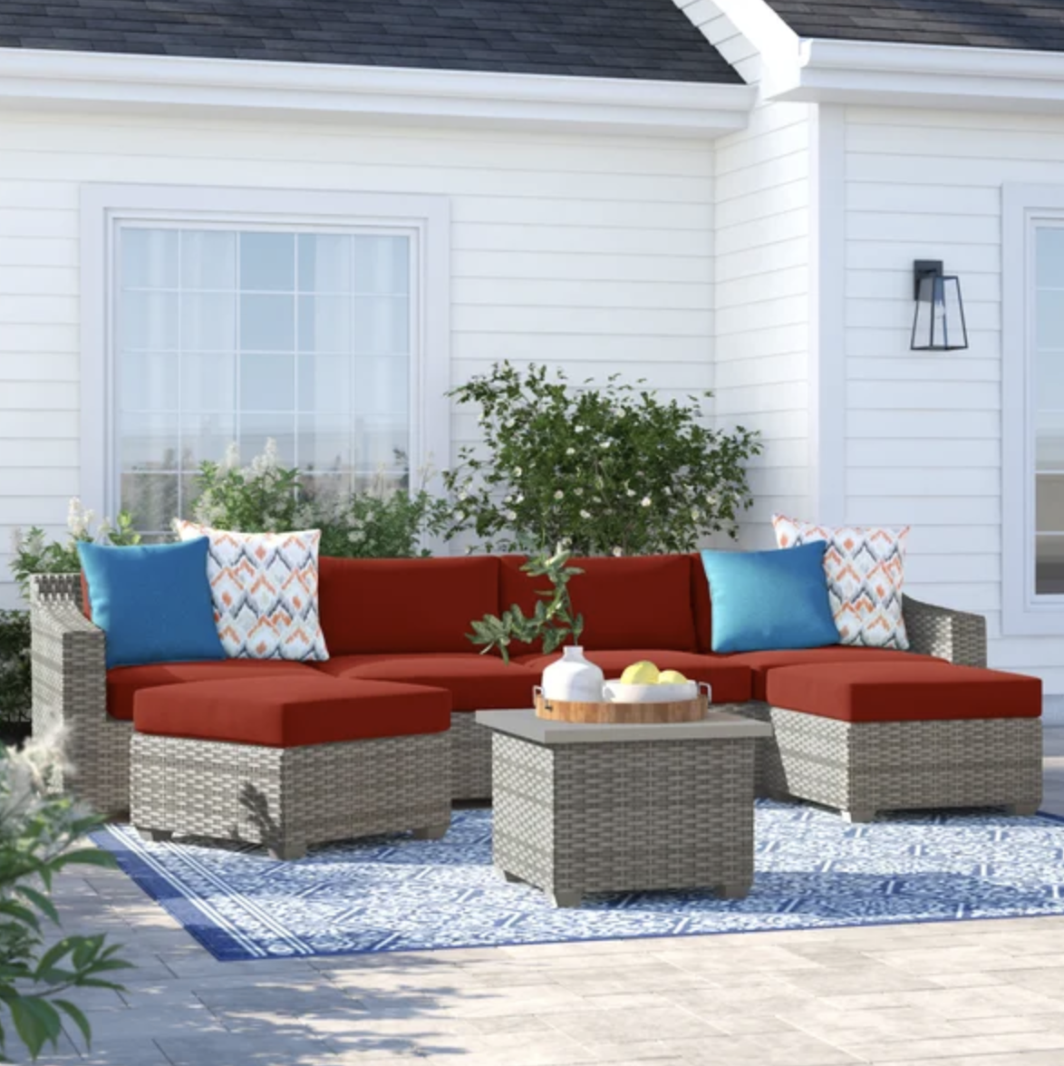 six-person outdoor wicker seating set with terracotta cushions and colorful pillows