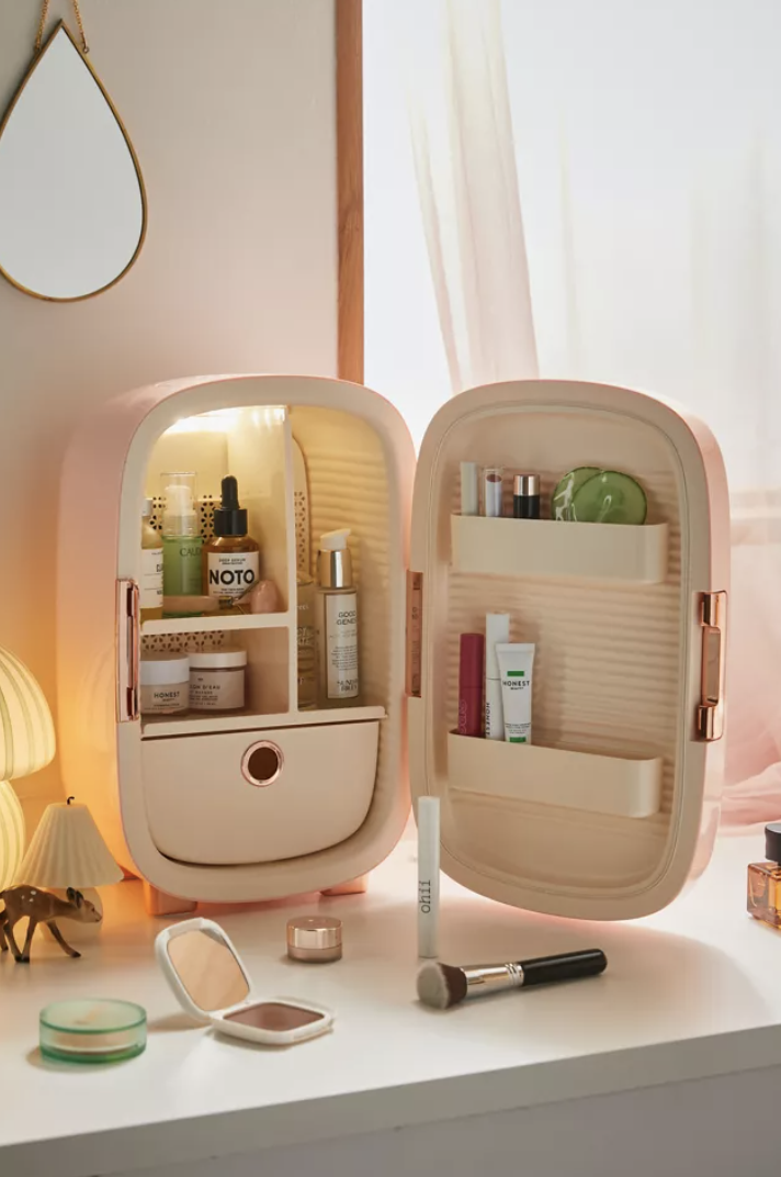 pink skincare fridge filled with jars and containers of cosmetics on vanity