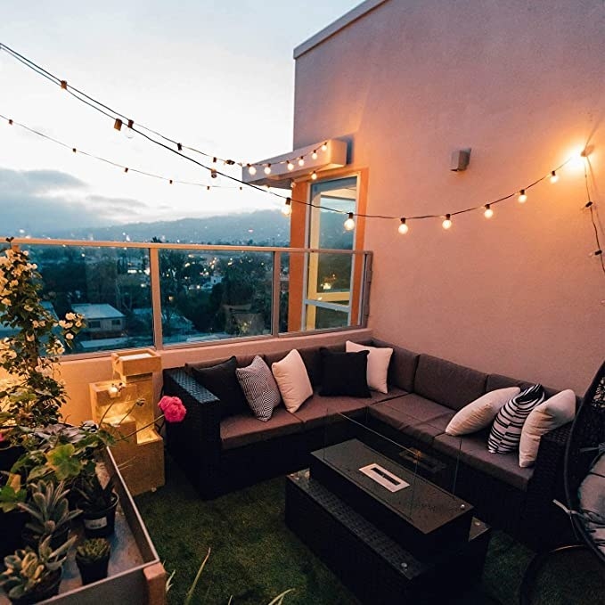 the string of lights hanging over outdoor furniture on a balcony