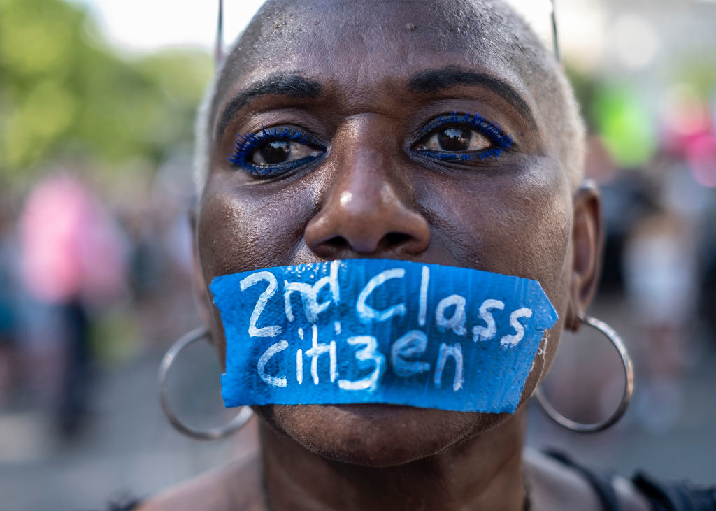 A woman with that slogan written on a piece of tape covering her mouth