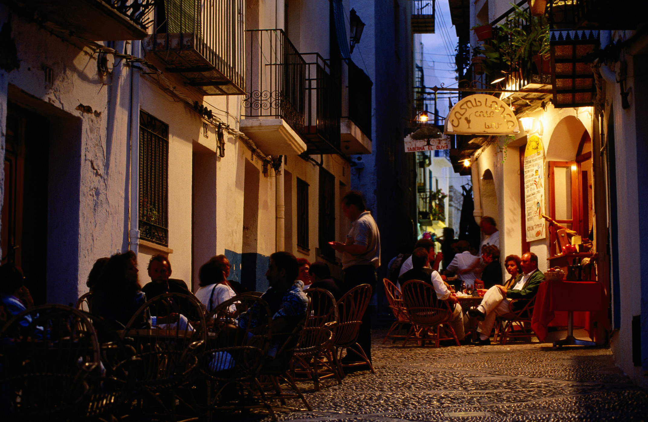 People eating outdoors at a restaurant at night.
