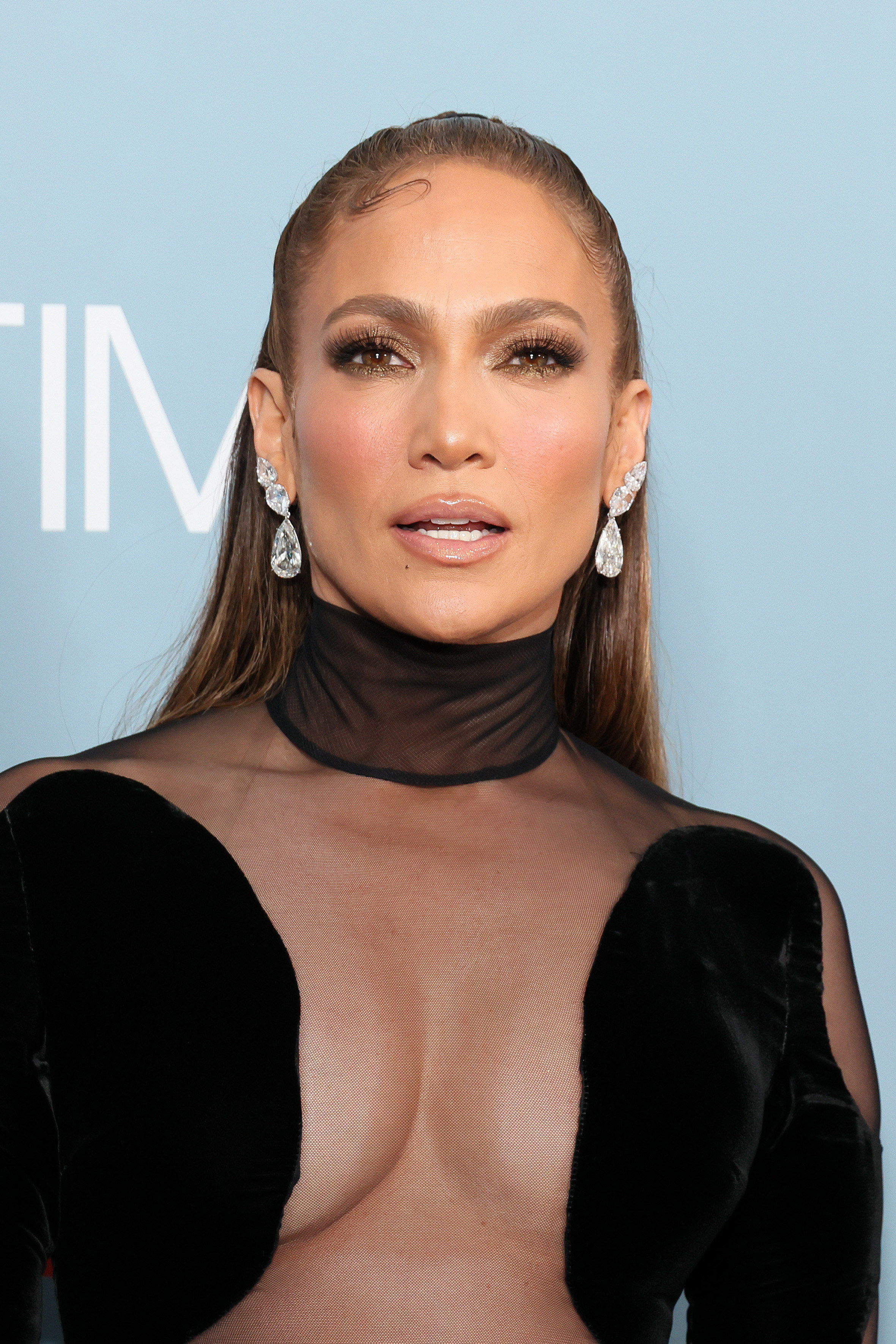 JLo in a transparent lacy cleavage-baring top with a choker