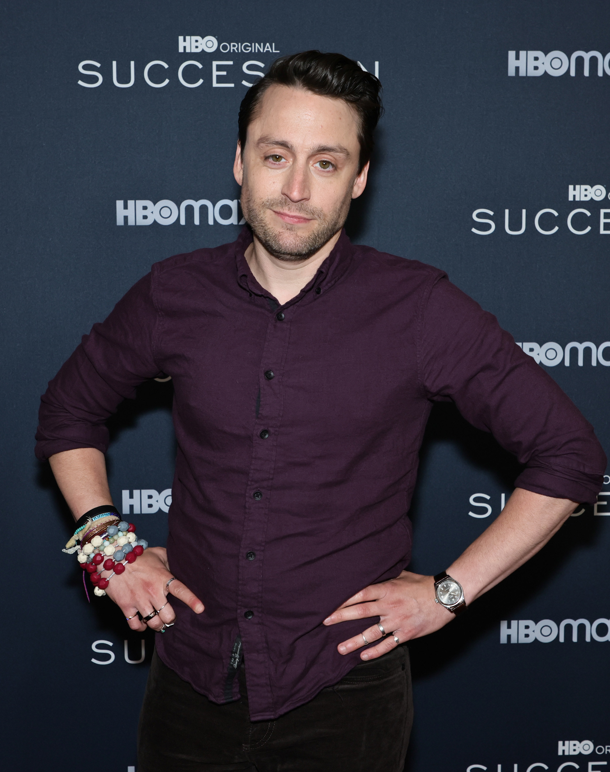 Culkin wearing a shirt with the sleeves rolled up and with hands on hips on the red carpet