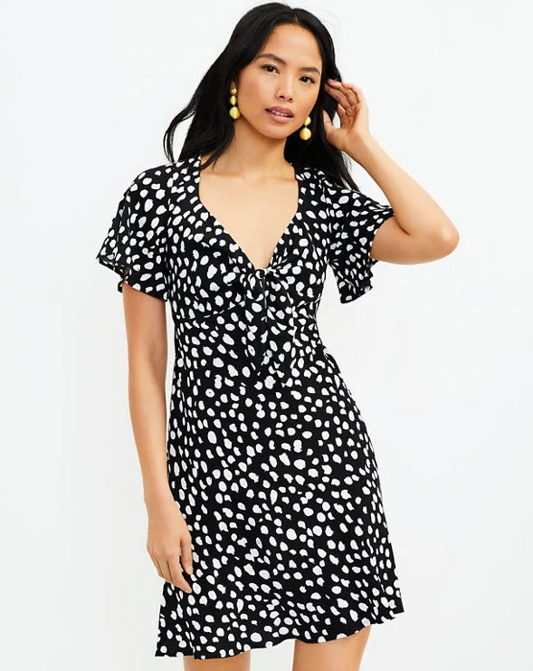 black mini dress with white poka dots and a tie front