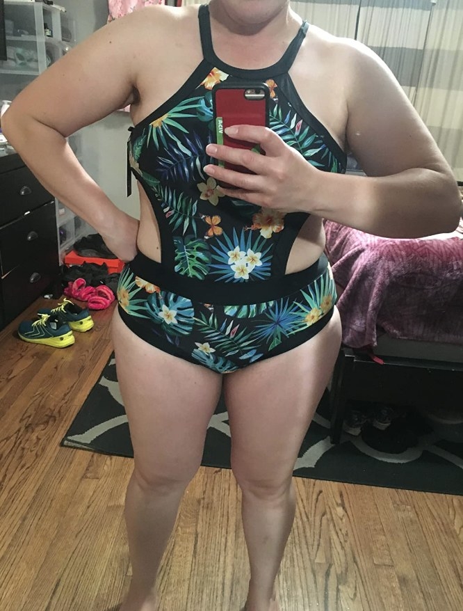 A reviewer wearing a black leaf cutout one piece swimsuit