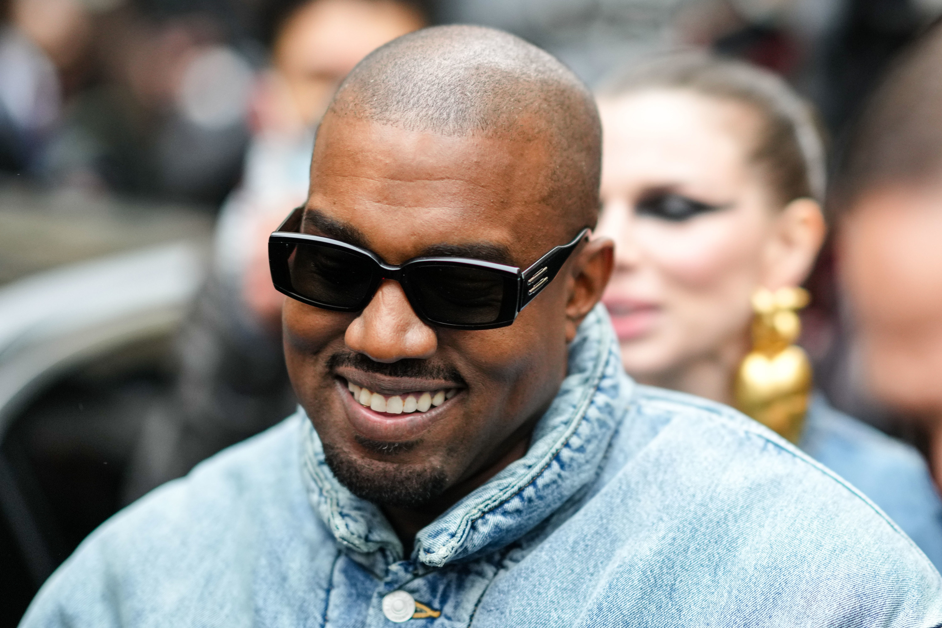 Kanye West smiling and wearing a denim puffer coat