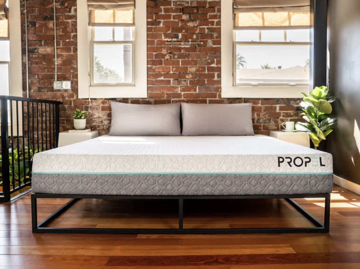 A mattress is shown on a bed frame in a bedroom