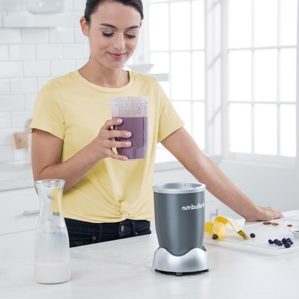 Model holding a smoothie in the blender cup turned drinking cup