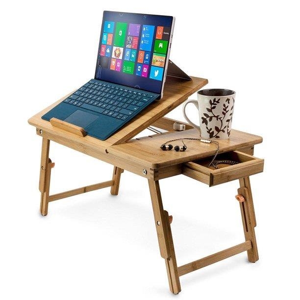 the bamboo desk tray with laptop propped up at angle on stand, coffee mug resting next to it and side drawer pulled out with headphones in it