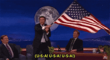 a person waving an american flag and chanting u s a