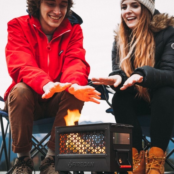 Two people sitting down next to the portable campfire
