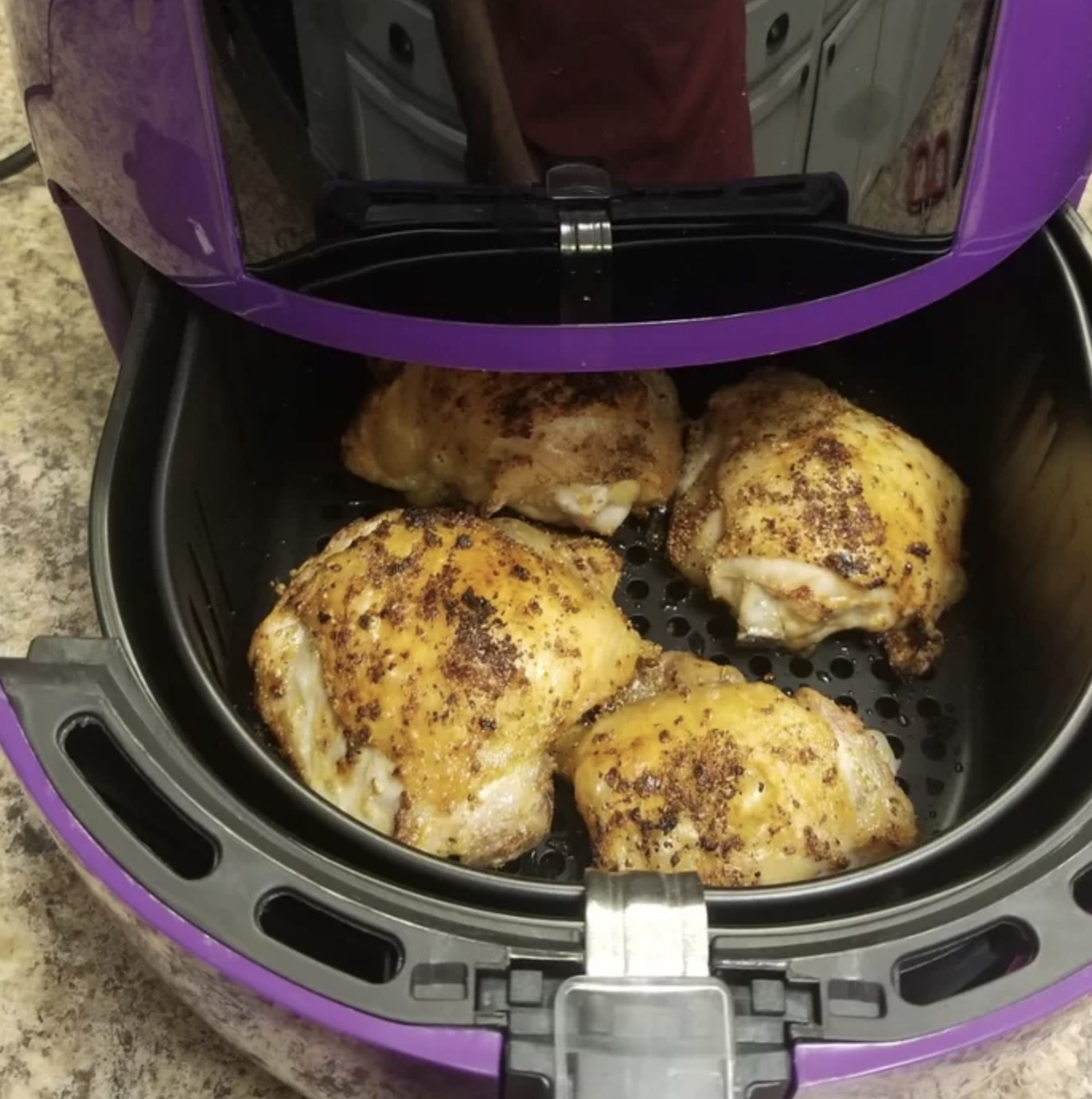 reviewer&#x27;s photo showing crispy chicken thighs inside the purple air fryer