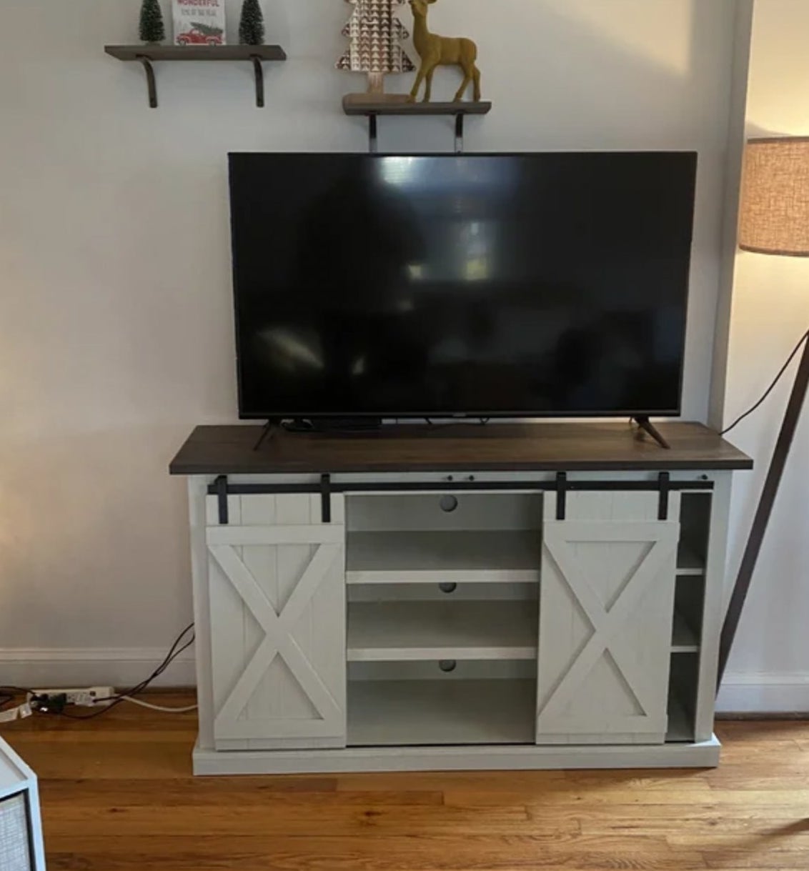 Reviewer&#x27;s photo of the white sliding barn door stand with tv perched on top