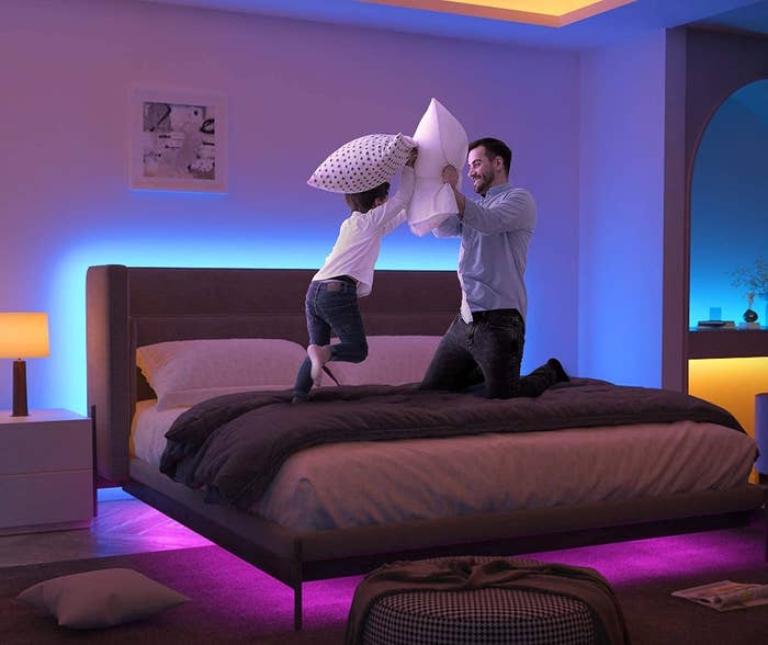 an adult and child having a pillow fight on a bed where the lights are wraps around