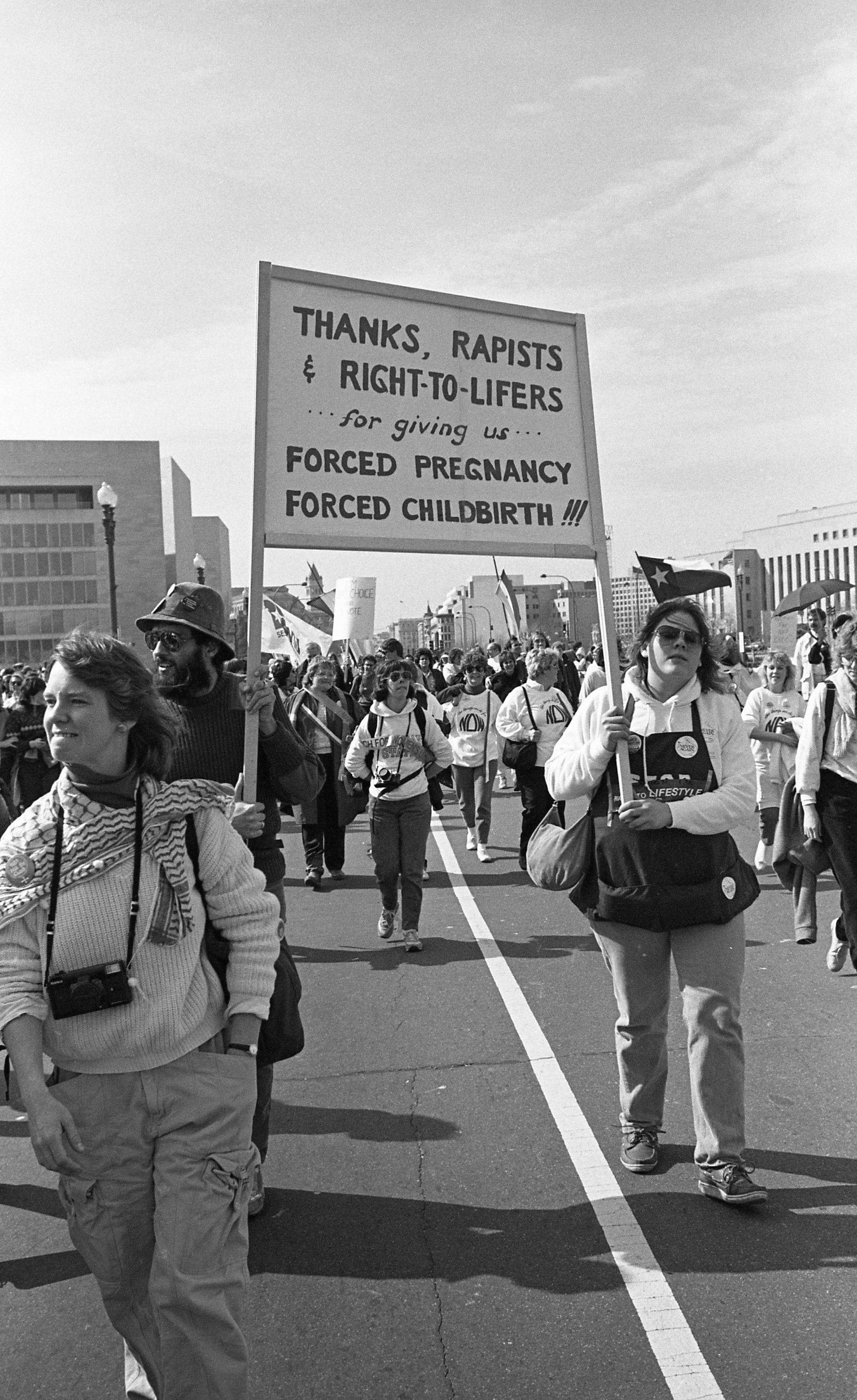 Demonstrators in a city street hold a sign reading &quot;thanks, rapists and right-to-lifers for giving us forced pregnancy and forced childbirth&quot;