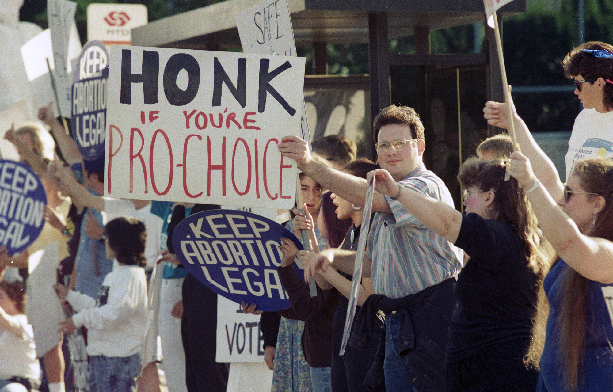 People line up along a street holding signs reading &quot;keep abortion legal&quot; and &quot;honk if you&#x27;re pro-choice&quot;