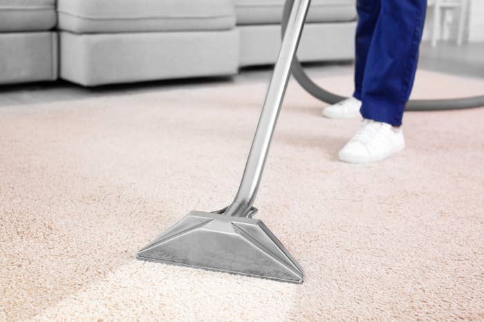 Someone vacuuming carpet