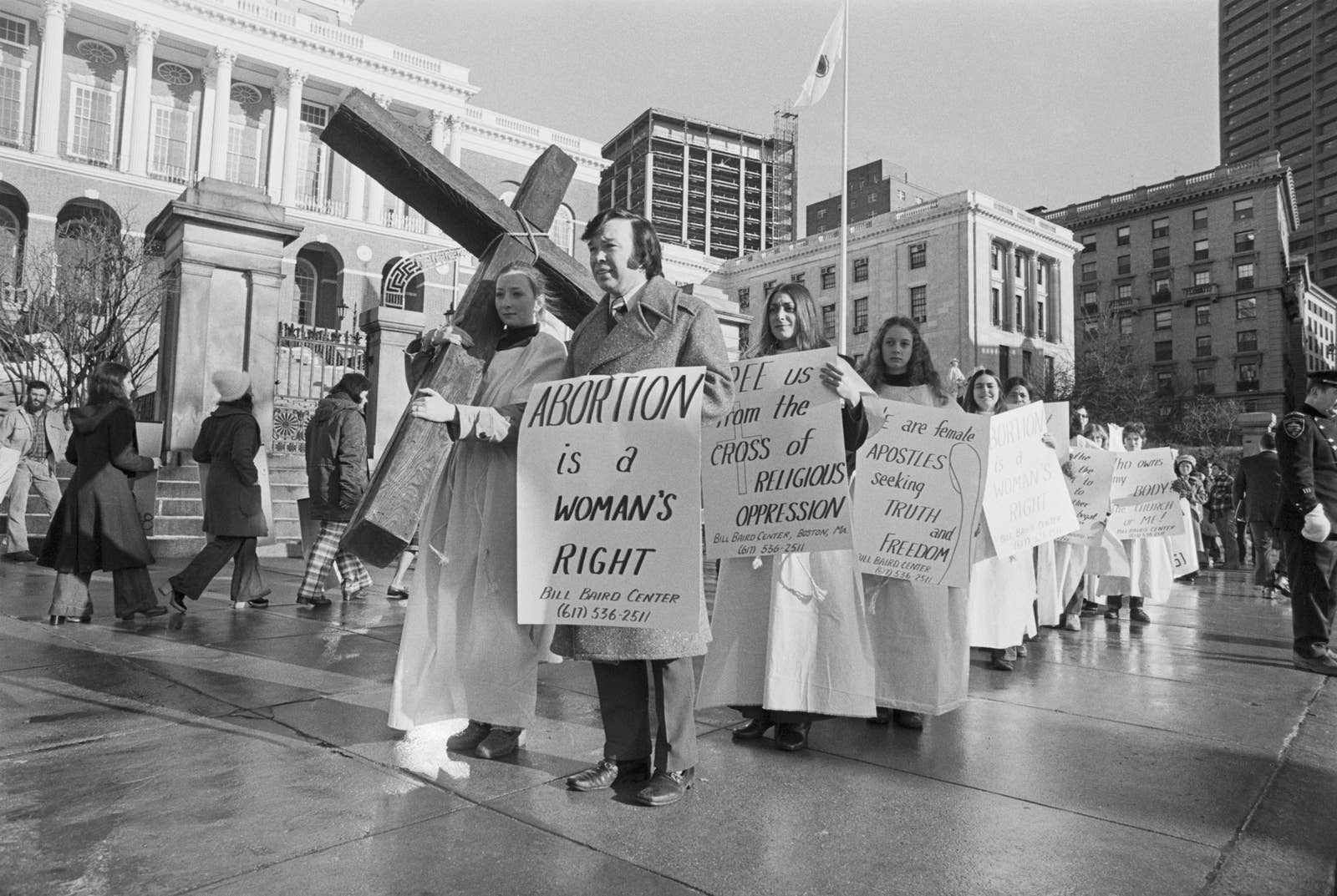 Protesters carry a cross and signs reading &quot;abortion is a woman&#x27;s right&quot; and &quot;free us from the cross of religious oppression&quot;