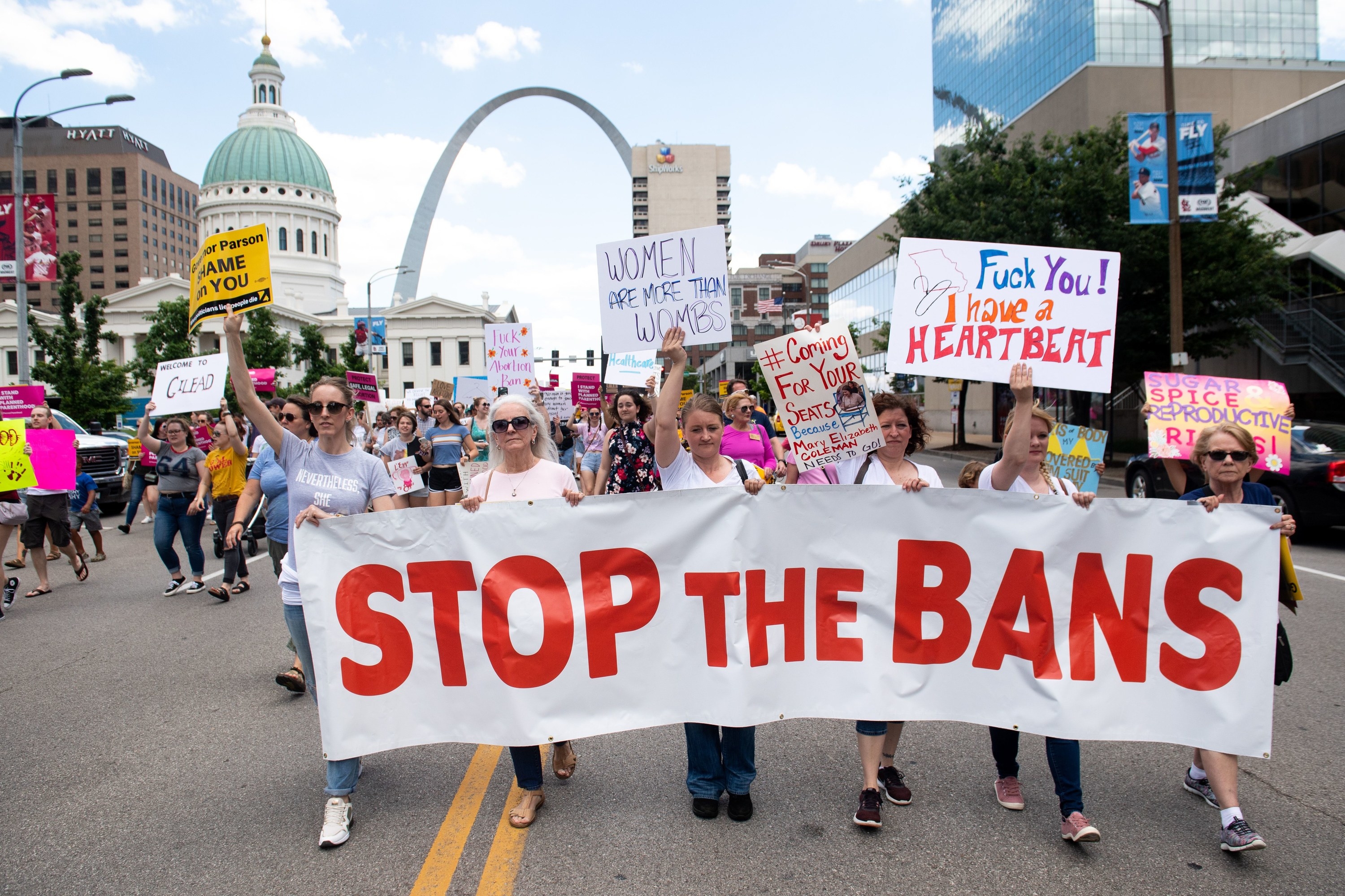 Demonstrators in the street hold signs reading &quot;women are more than wombs&quot; and &quot;stop the bans&quot;