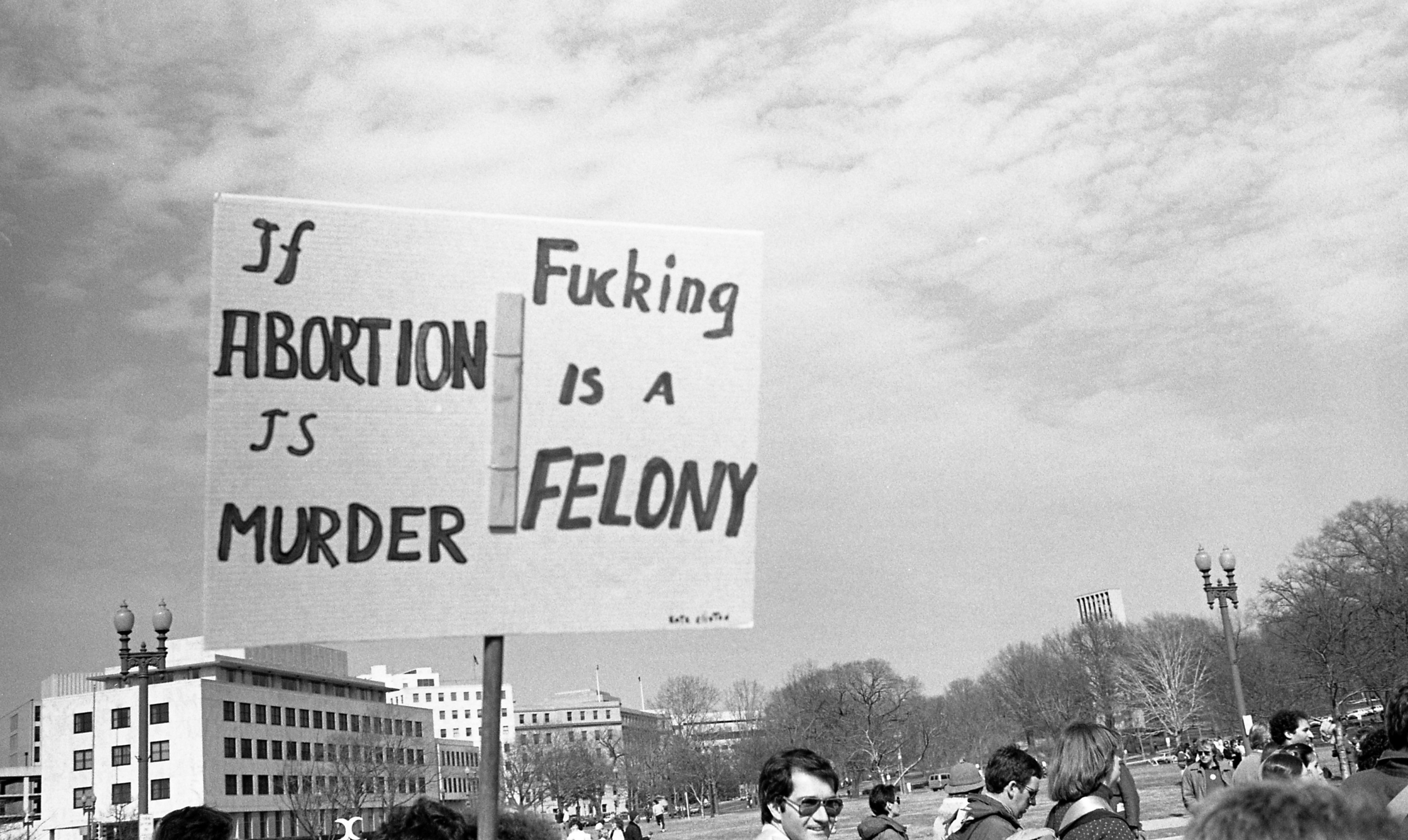 A protester holds a sign that reads &quot;if abortion is murder, fucking is a felony&quot;