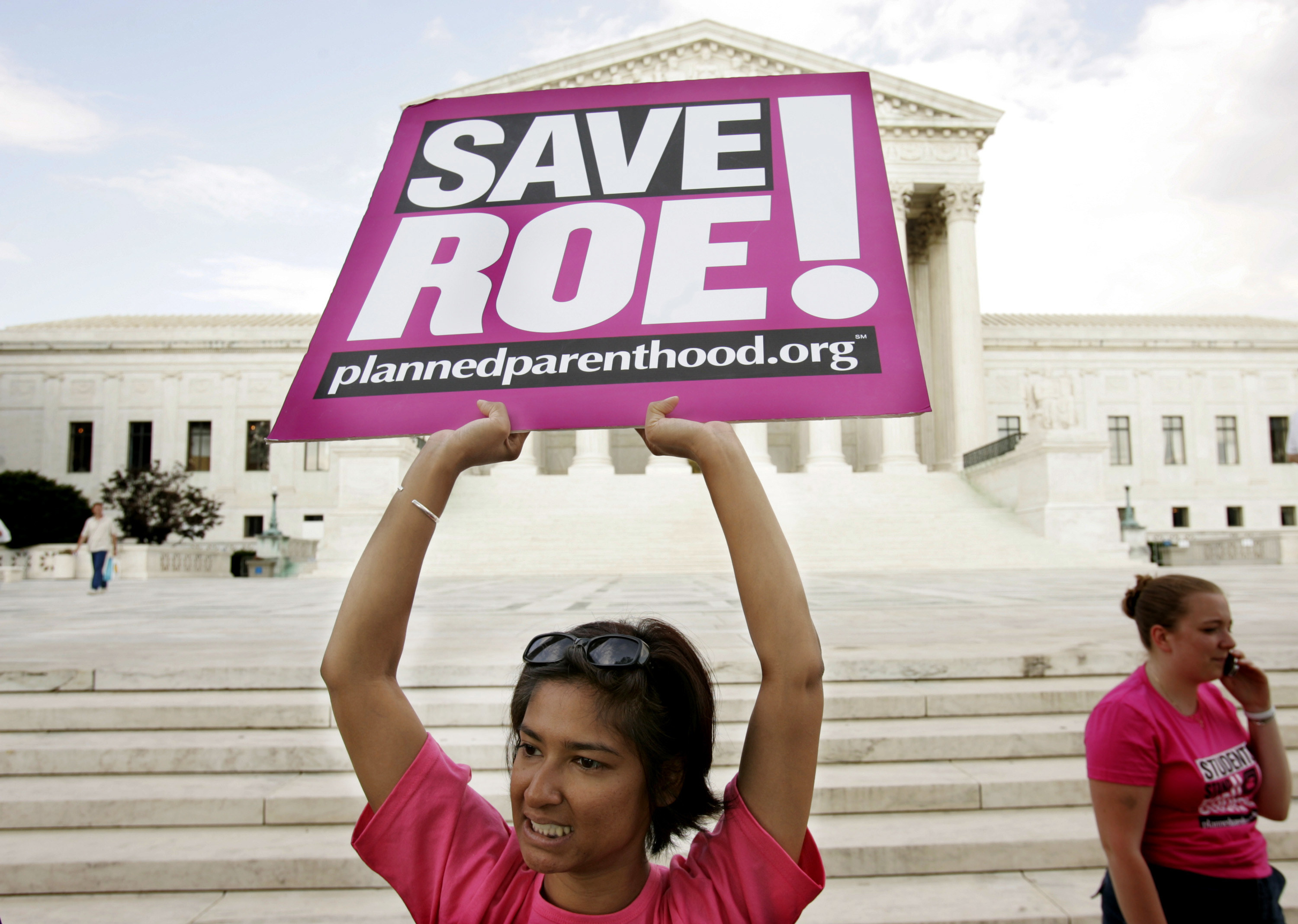 A protester holds up a sign reading &quot;Save Roe&quot; in front of the Supreme Court steps