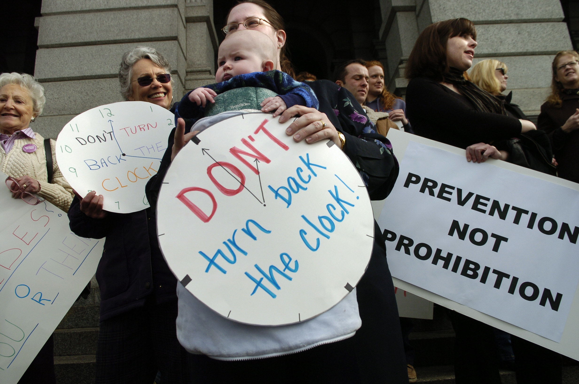 Protesters hold signs reading &quot;don&#x27;t turn back the clock&quot; and &quot;prevention not prohibition&quot;