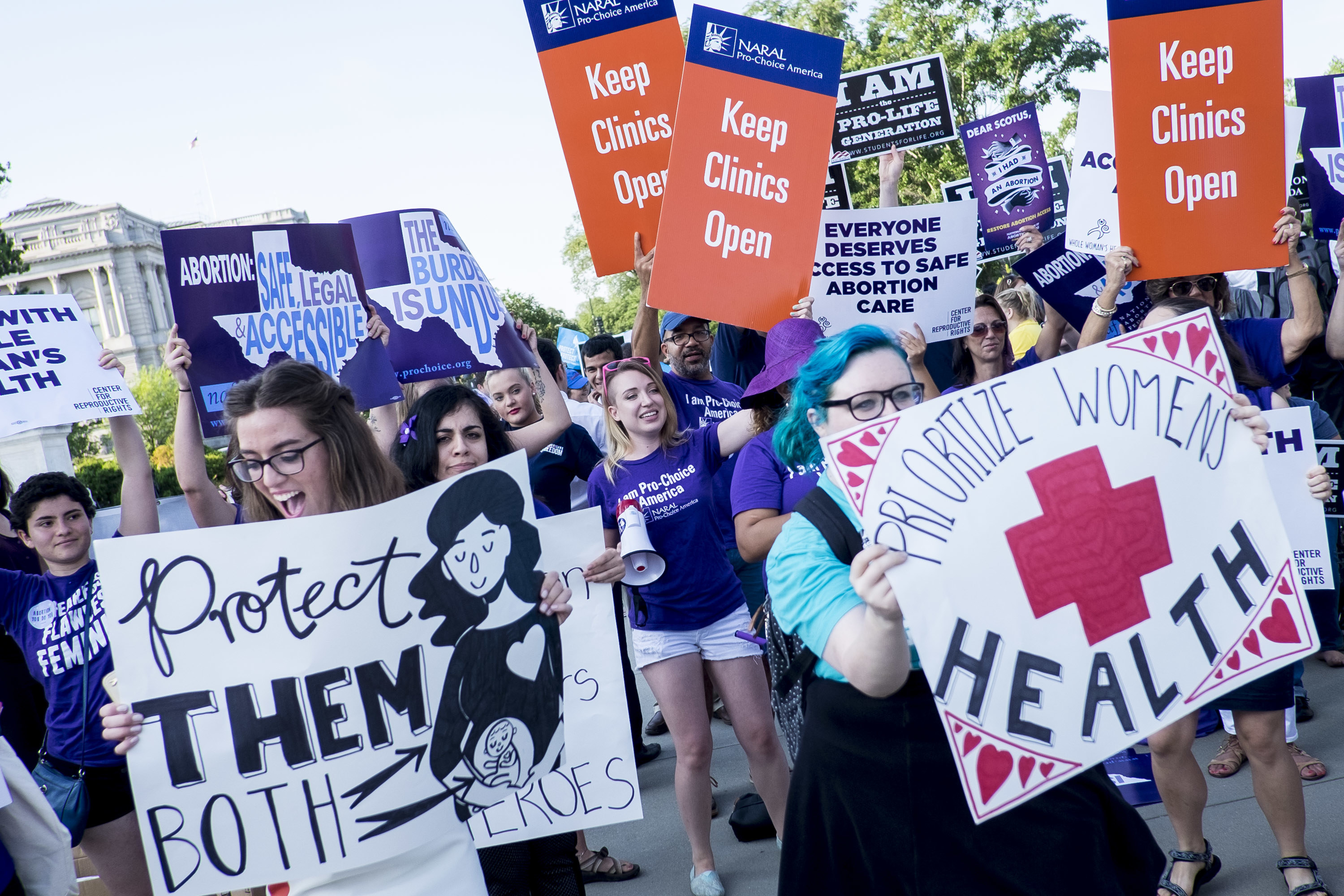 Demostrators hold signs reading &quot;keep clinics open&quot; and &quot;prioritize women&#x27;s health&quot;