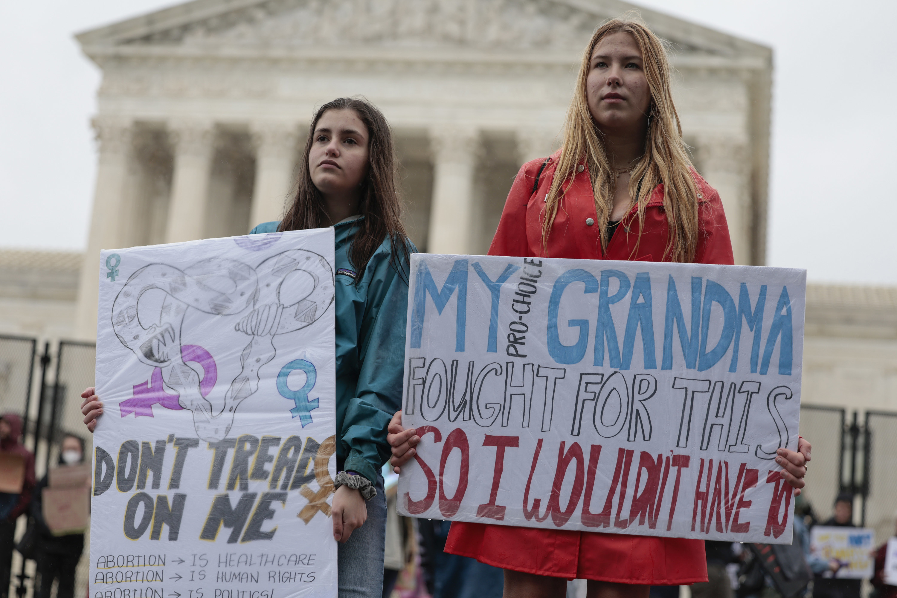 Two demonstrators hold signs reading &quot;don&#x27;t tread on me&quot; and &quot;my pro-choice grandma fought for this so I wouldn&#x27;t have to&quot;