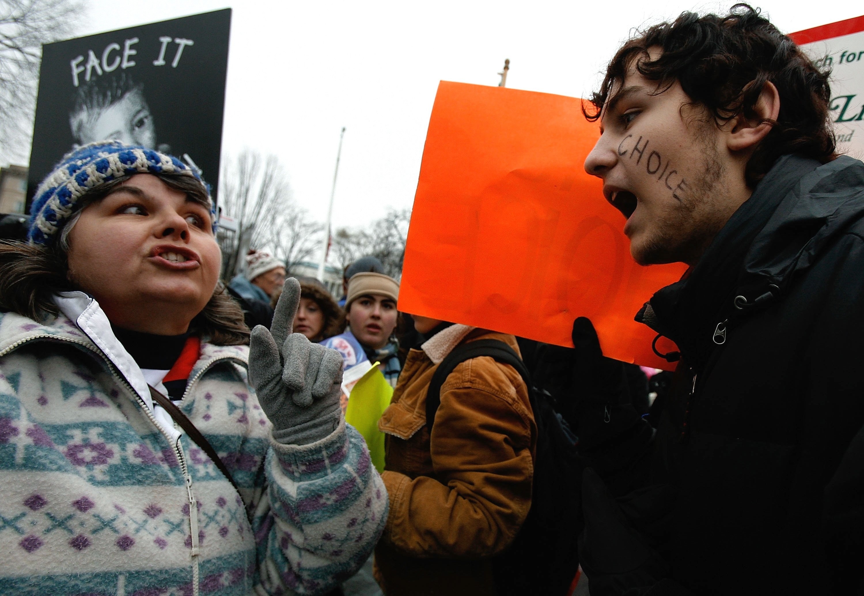 People carrying signs outside talk passionately at each other