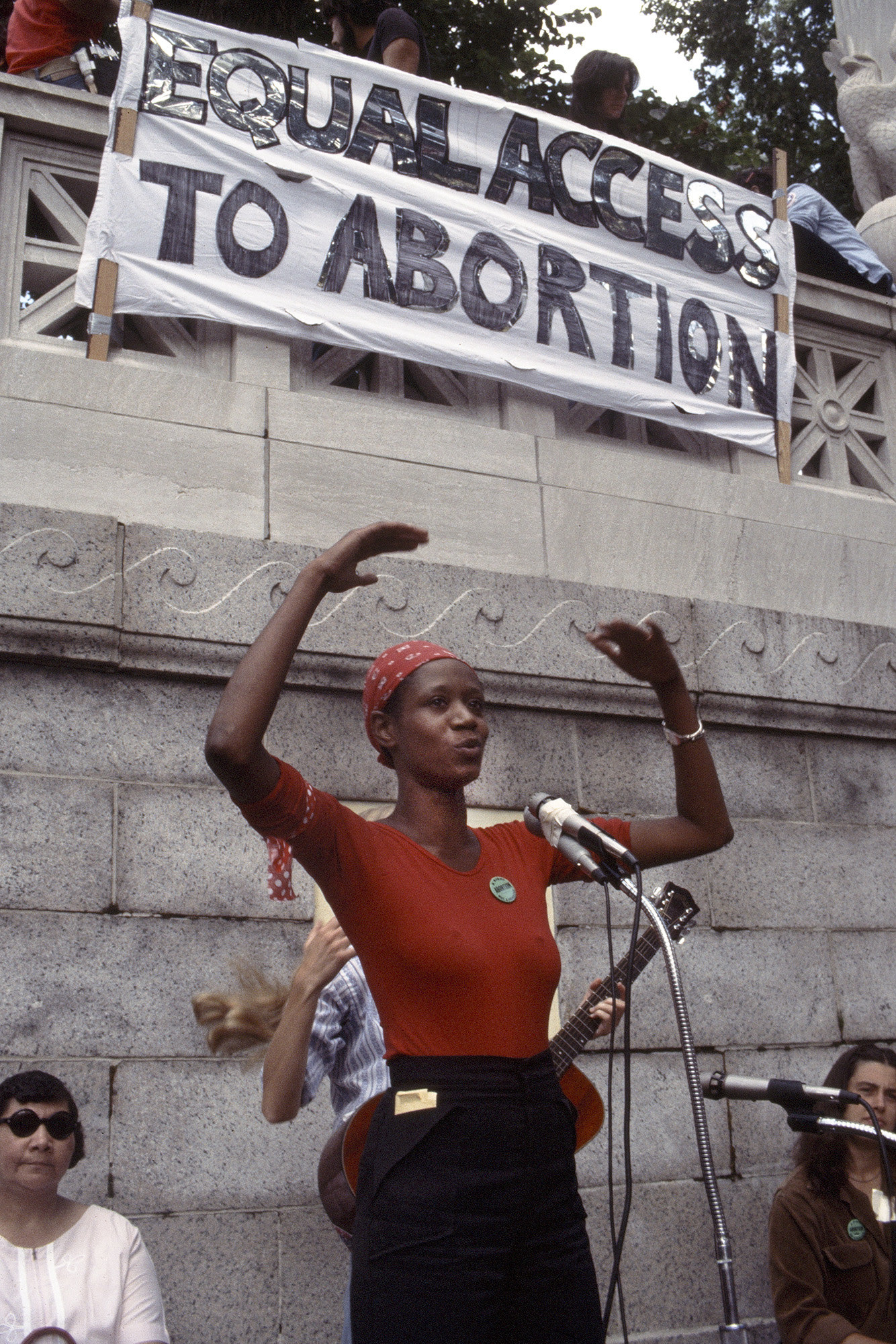 A woman stands behind a microphone outside