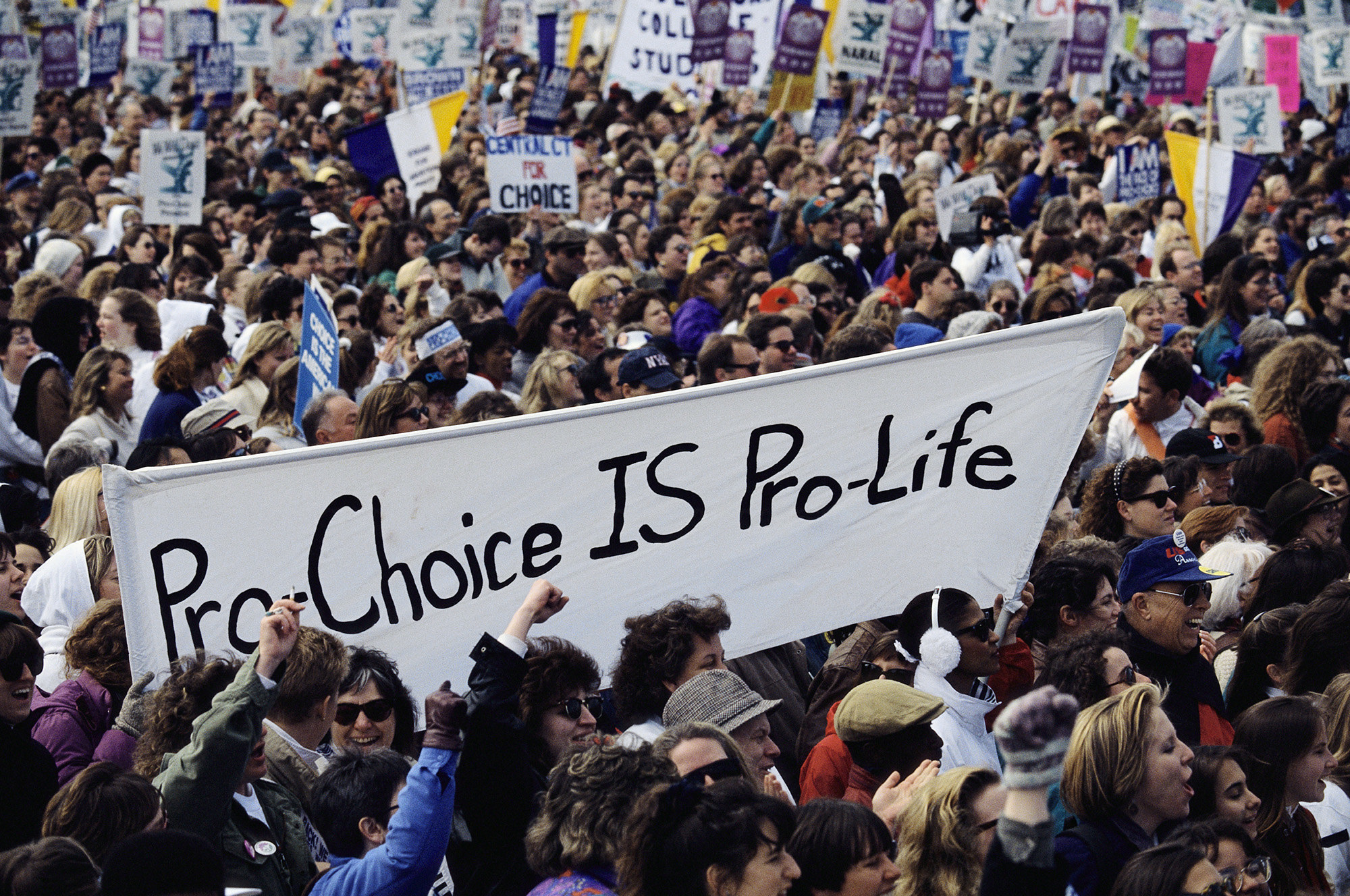 A banner held by demonstrators in a large crowd reads &quot;pro-choice is pro-life&quot;