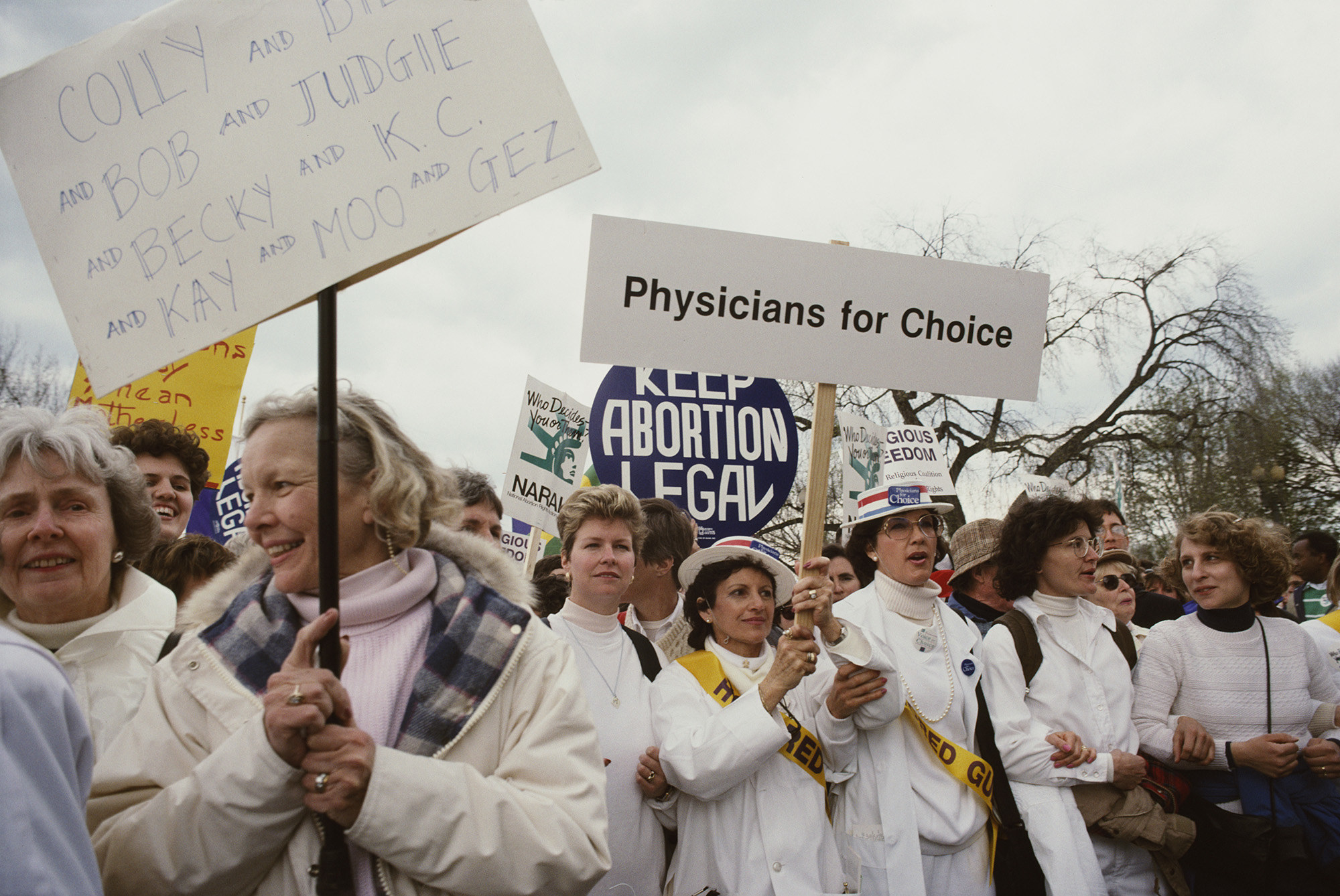 Women wearing white hold up signs reading &quot;physicians for choice&quot; and &quot;keep abortion legal&quot;