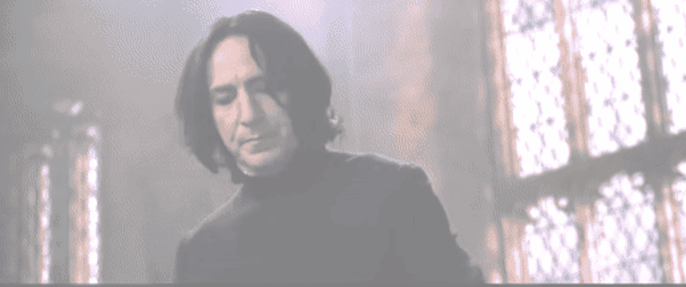 Snape grabs Malfoy while a camera crew watches on in the background