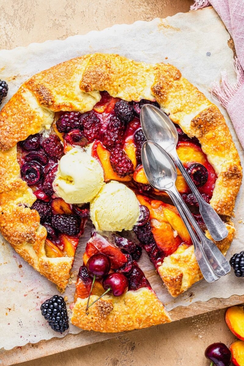 A galette with blackberries and peaches topped with ice cream.