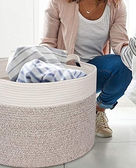 A person transferring clothes from the dryer to the woven basket