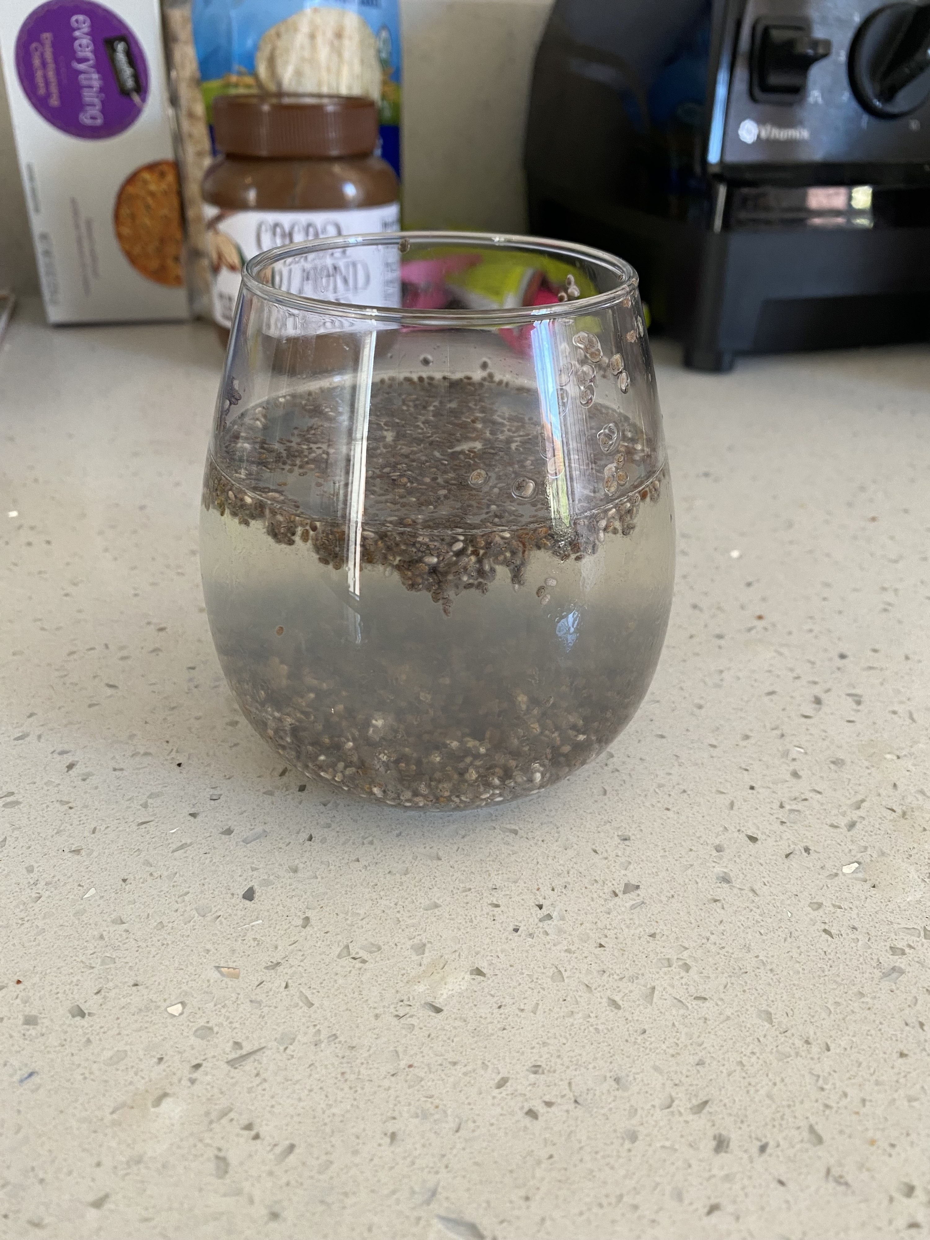 The previous half-full glass of water, but now most of the chia seeds have sunk to the bottom of the glass