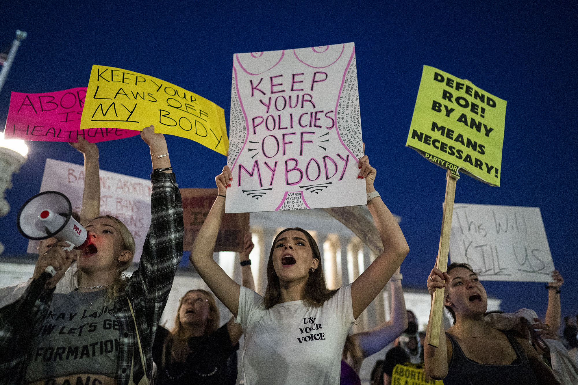 Demonstrators hold signs reading &quot;keep your policies off my body&quot; and &quot;defend Roe by any means necessary&quot;