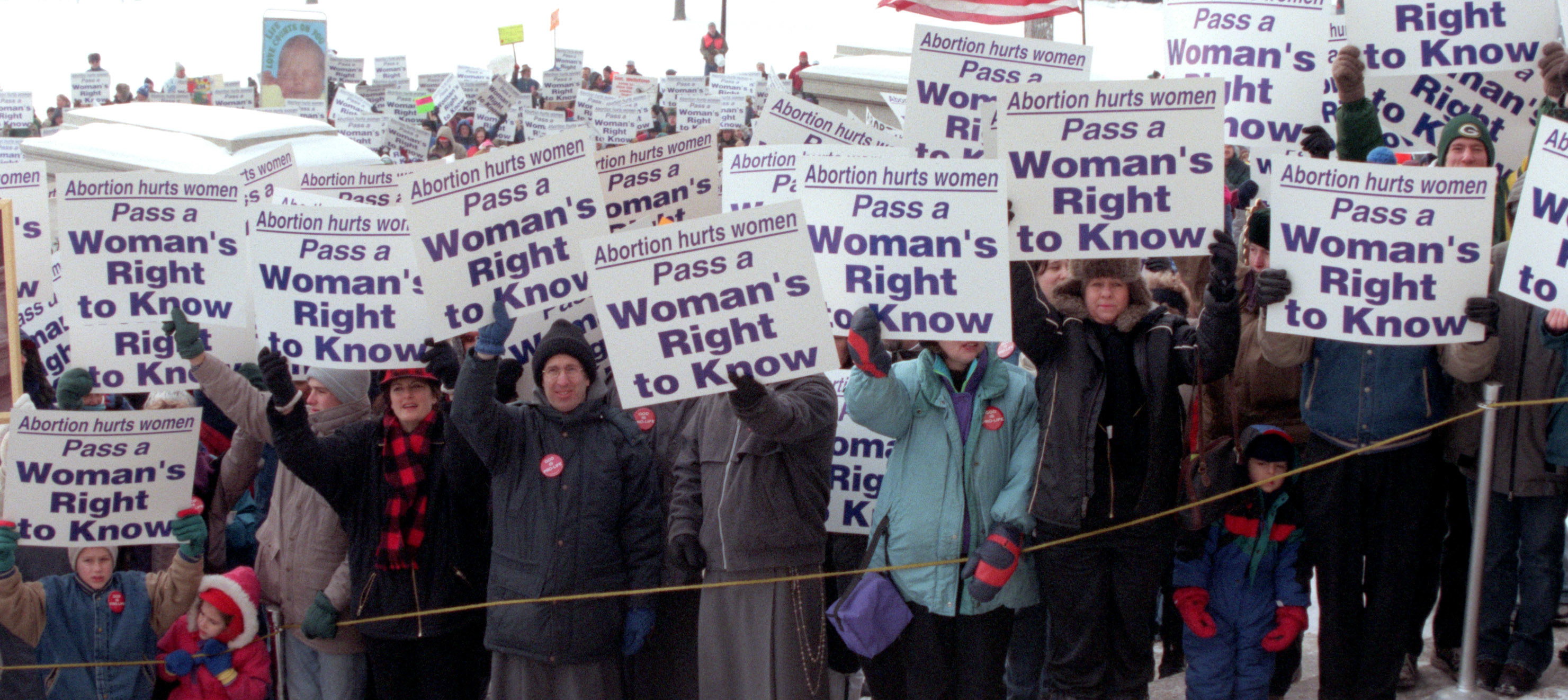 Demonstrators hold up signs reading &quot;pass a woman&#x27;s right to know&quot;