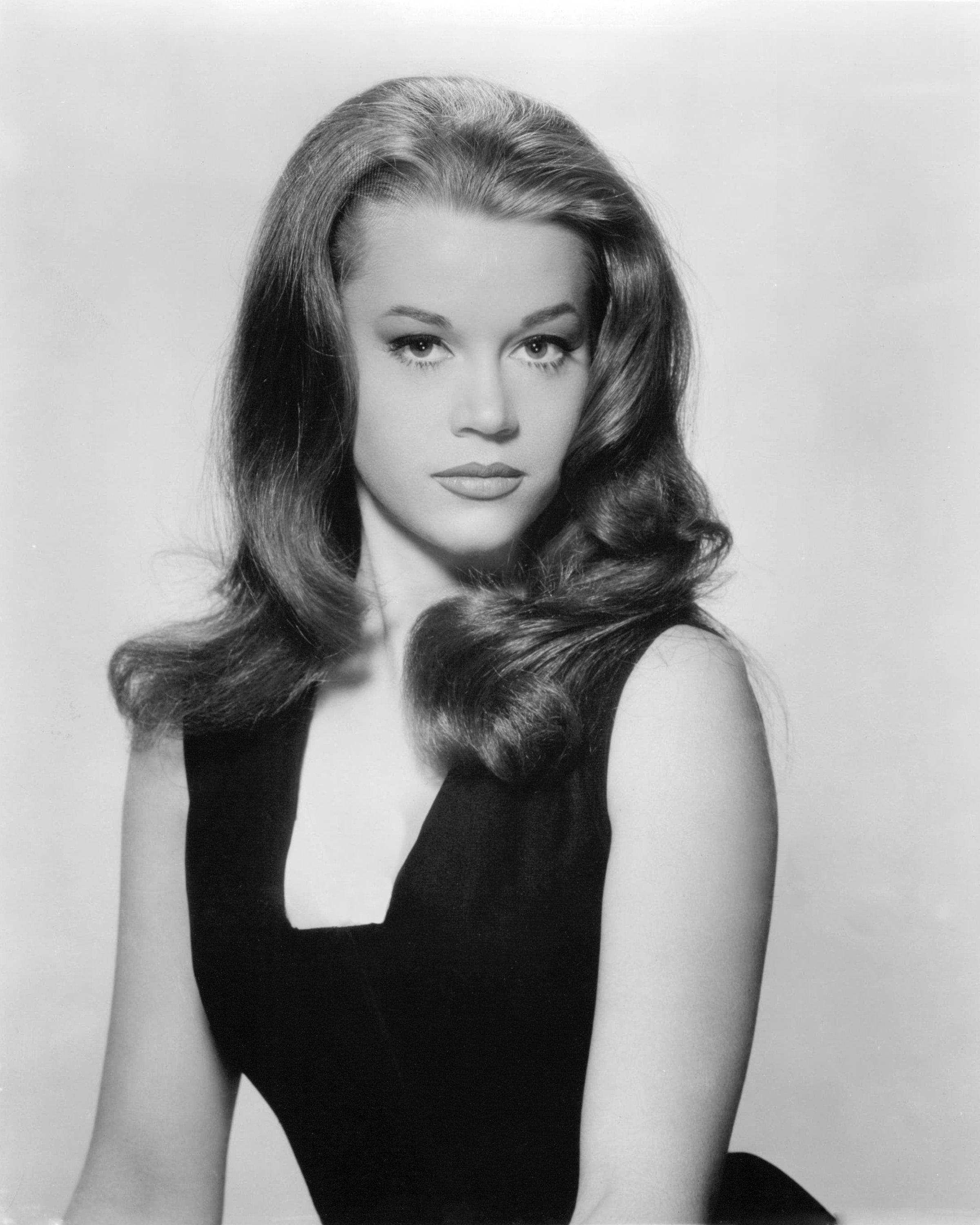 Young Jane Fonda posing in a black dress