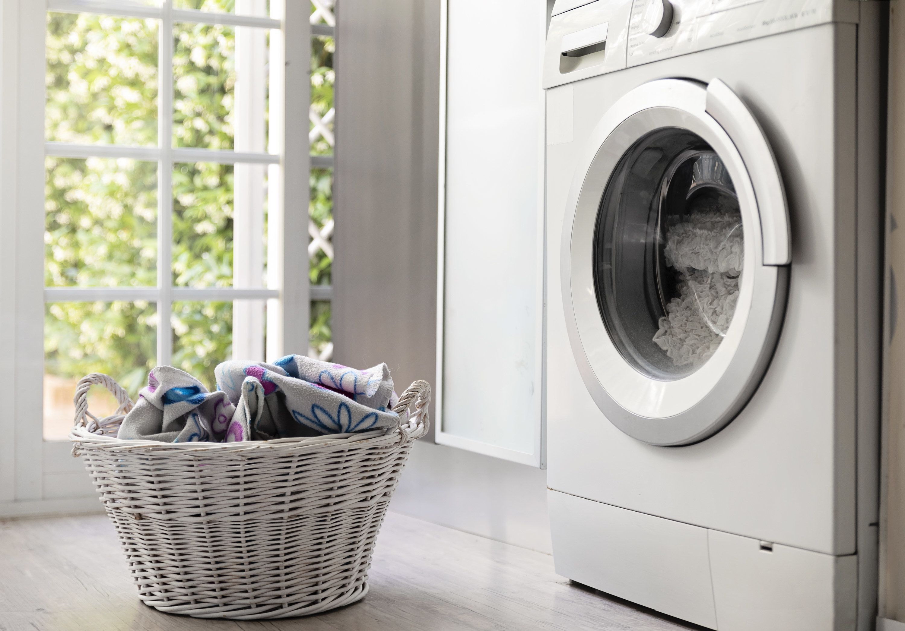 A laundry basket sits next to a washing machine