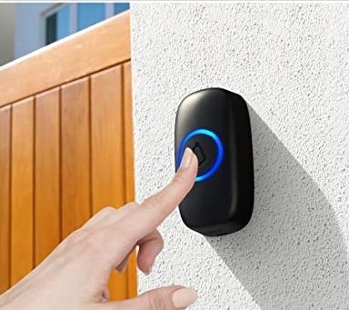 a person pressing the doorbell button on a wall