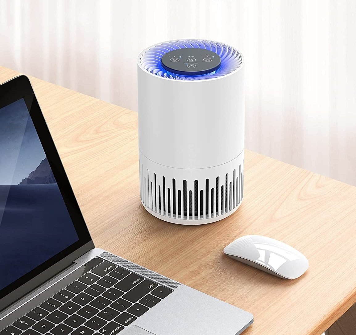 the desktop purifier on a desk next to a laptop