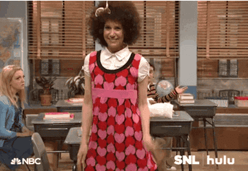 Kristin Wiig in an afro wig and pink heart patterned dress dancing
