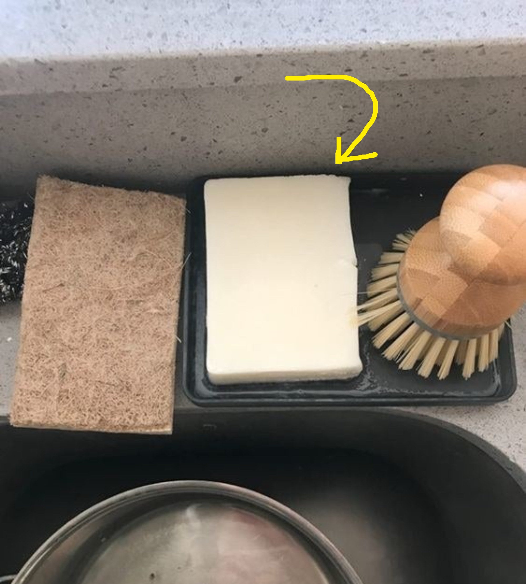 Reviewer's photo of the soap sitting on kitchen sink next to sponge