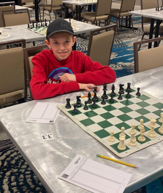 Brody smiling while sitting in front of a chess board