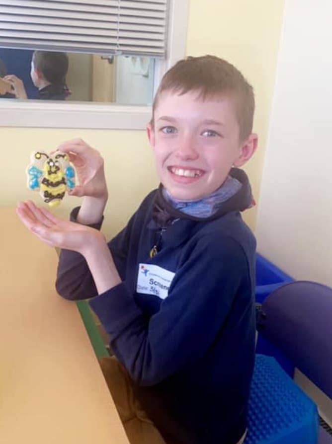 Brody smiling and posing with a cookie made to look like a bee
