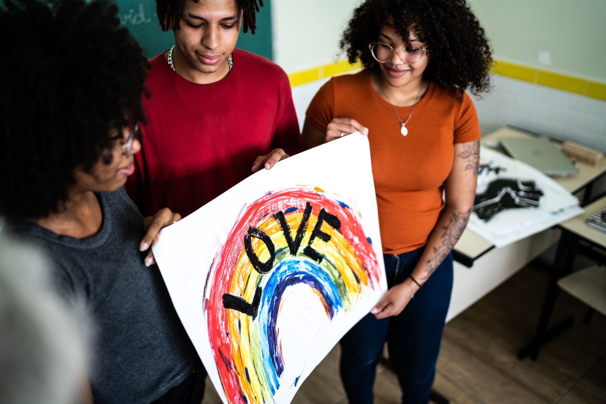 students holding a rainbow poster with love written on it