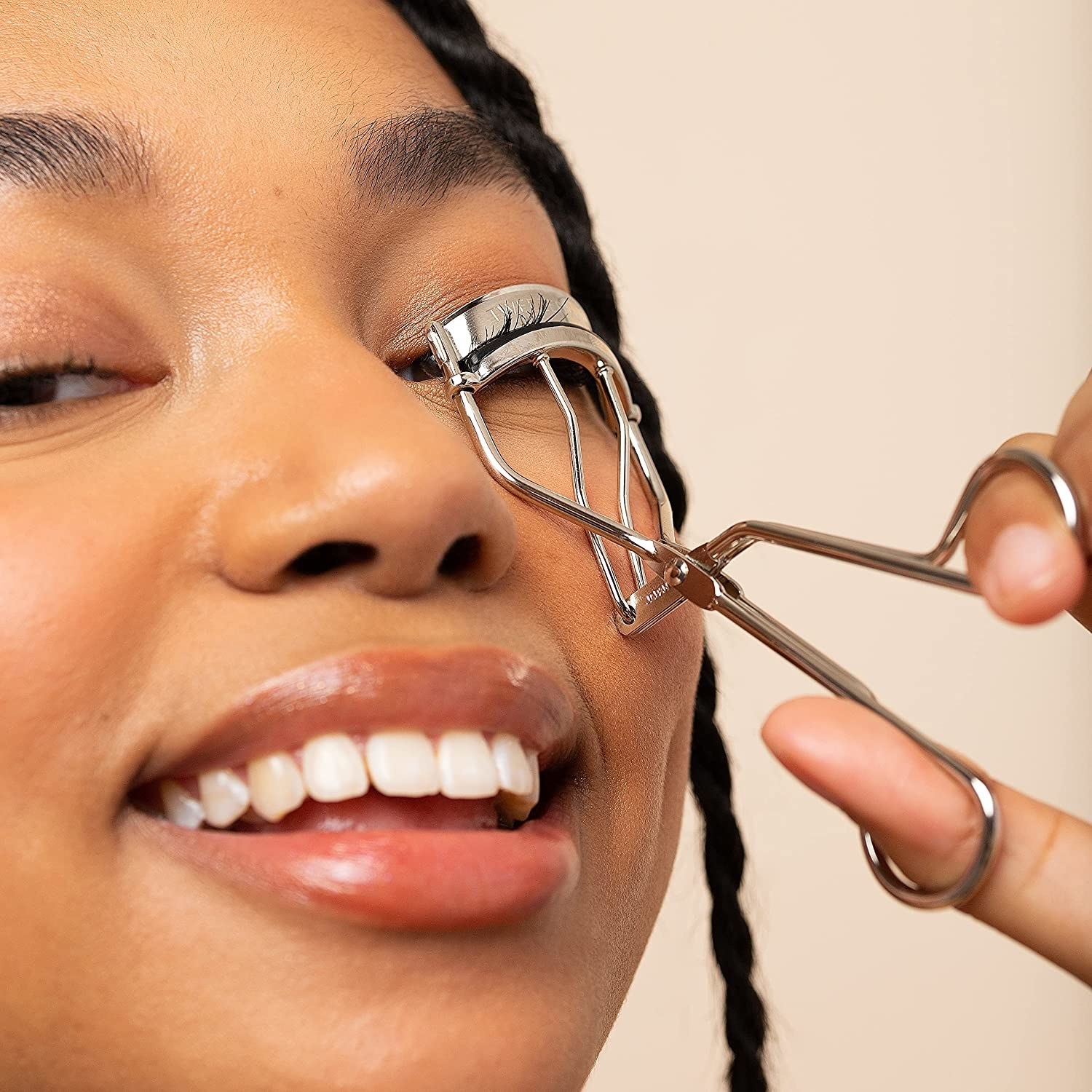 A person using the eyelash curler to curl their lashes