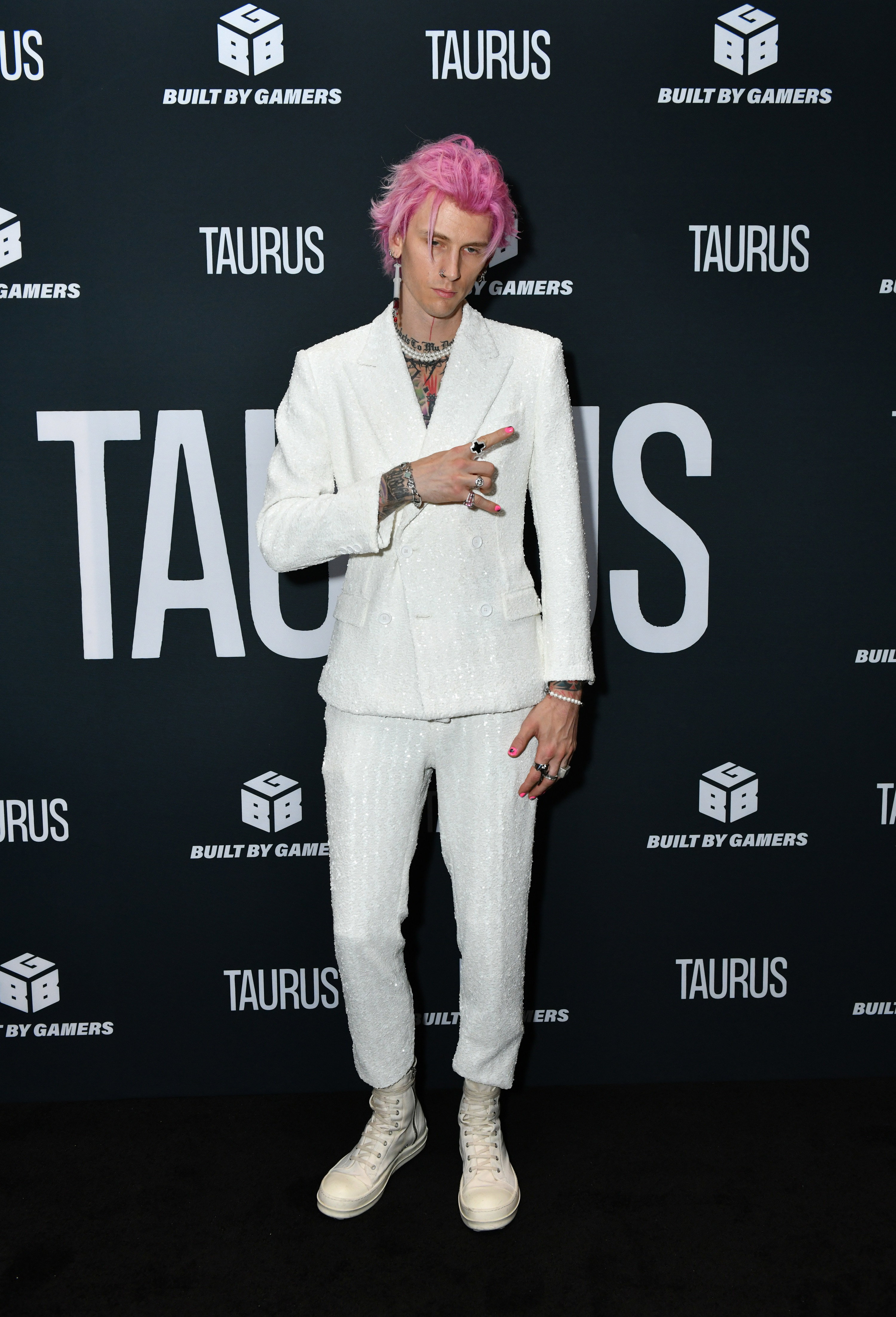 MGK pulling a &quot;rock n roll&quot; finger sign in a suit at the premiere of &quot;Taurus&quot;