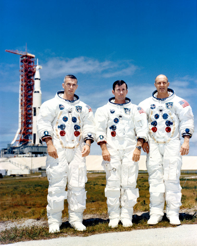 Three astronauts in their spacesuits standing on grass